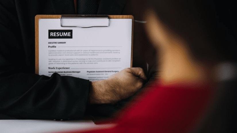 Person holding a resume clipboard during a job interview.